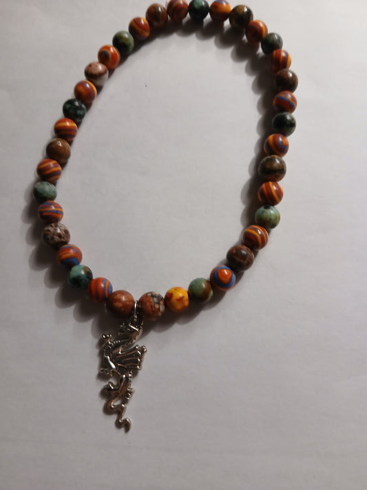 Homemade bracelet. Multi colored lava rock beads with a silver dragon charm.